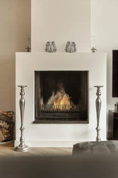 a living room with a fire in the fireplace and two vases on the table next to it, as well