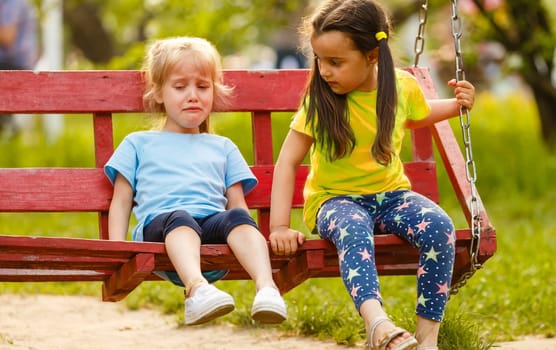 Sad baby girl crying in the park with the swing broken