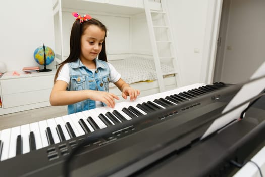 a cute little girl learning to play the synthesizer
