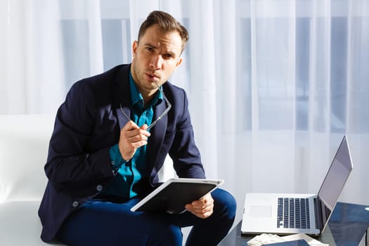 Handsome young man working while sitting on the couch in office.