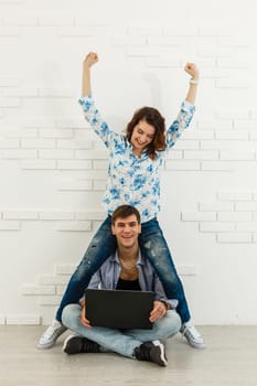 Portrait of happy young couple using laptop on gray background.