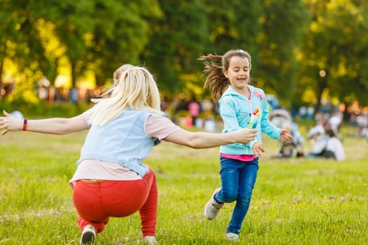 beautiful young mother and her daughter having fun at the field.