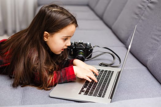 education, free time, technology and internet concept - little student girl with laptop pc at home.