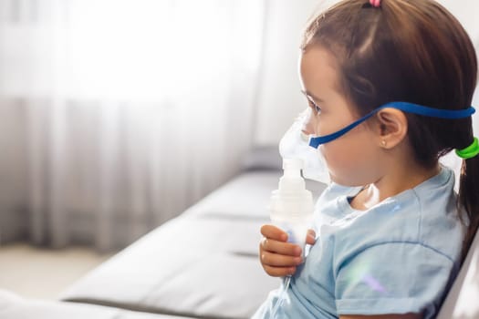 Little girl in a mask, treatments respiratory tract with a nebulizer at home