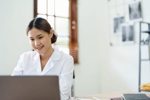 Portrait of an Asian doctor using a computer.