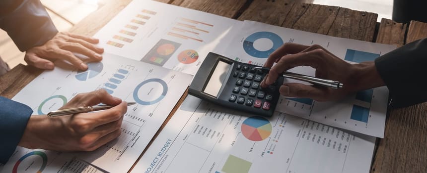 Business People Meeting using laptop computer,calculator,notebook,stock market chart paper for analysis Plans to improve quality next month. Conference Discussion Corporate Concept....