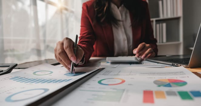 Close up Business woman using calculator and laptop for do math finance on wooden desk in office and business working background, tax, accounting, statistics and analytic research concept