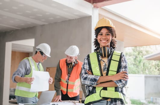 Leadership Concept by Female Engineers : Portrait of a happy female engineer in front of a group of male construction workers : Effective teamwork..