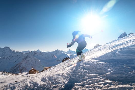 A young female skier quickly descends the slope in the alpine mountains. Winter sports and recreation, active recreation.