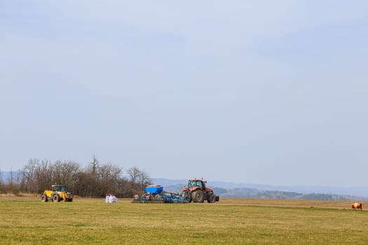 Tractor seeder and bags with seeds in the field. Modern technology in the field of agriculture.