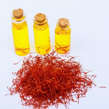 A pile of dry saffron stamens and a serving of saffron drink in cans on a white background. Infused tea from dry saffron stamens.