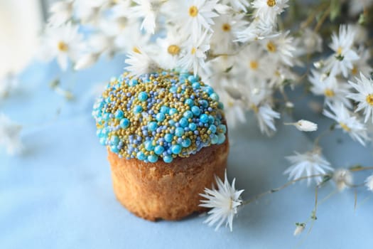 Orthodox Easter cake decorated with beads and daisies in the blue background