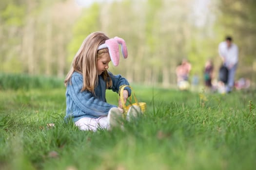 Girl with bunny ears collects the eggs in a basket for Easter
