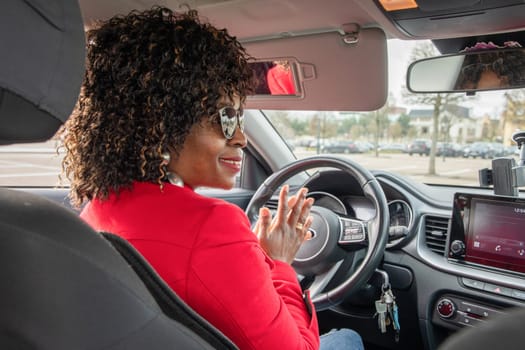 Pretty african american woman in car talking to neighbor in car while standing in parking, High quality photo