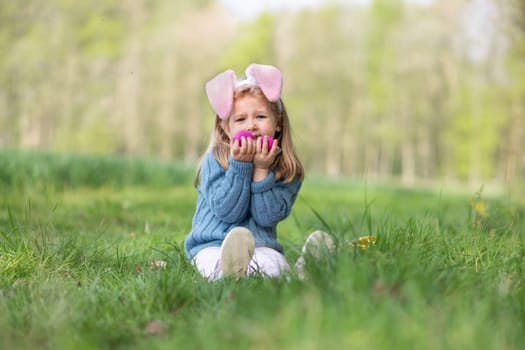 Girl with bunny ears collects the eggs in a basket for Easter