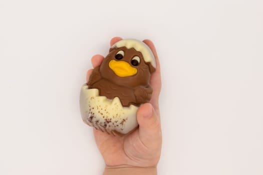 Kid holding figure of isoleted chocolate chicken hatched from an egg for Easter