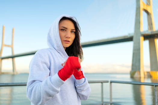 Female boxer in fighting stance staring into the frame, looking in camera powerful and confident women in boxing. Woman fighter, concept of strong woman and self defence.