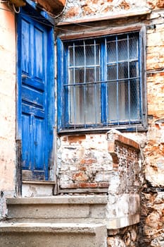 Door and window painted blue colour on facade of old village house, vertical frame