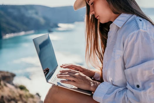 Happy girl doing yoga with laptop working at the beach. beautiful and calm business woman sitting with a laptop in a summer cafe in the lotus position meditating and relaxing. freelance girl remote work beach paradise