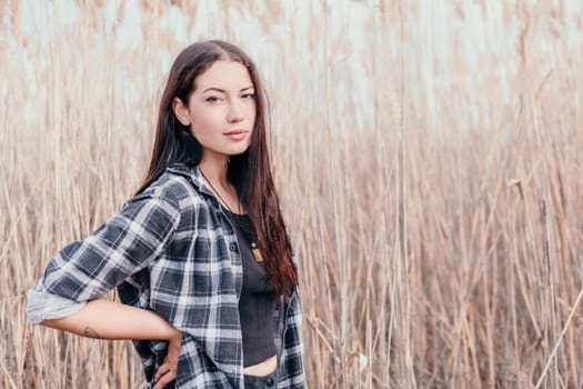 Happy young smiling woman with freckles outdoors portrait. Soft sunny colors. Outdoor close-up portrait of a young brunette woman and looking to the camera, posing against nature background.