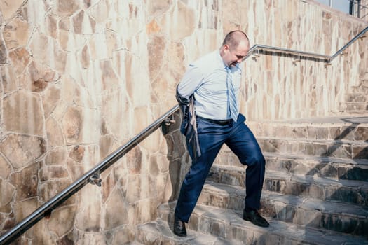 Portrait of a senior professional man in a suit with various problems. A middle-aged businessman with a briefcase descends the stairs.
