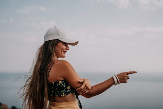 Woman travel sea. Happy tourist taking picture outdoors for memories. Woman traveler looks at the edge of the cliff on the sea bay of mountains, sharing travel adventure journey.