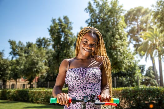 Young African American woman on an electric scooter looking at camera. Lifestyle concept.