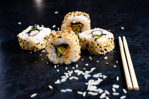 Sushi on black table with wooden chopsticks. Eating japanese food at restaurant.