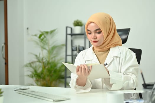 Beautiful Asian muslim businesswoman checking his working schedule plan at her workstation.