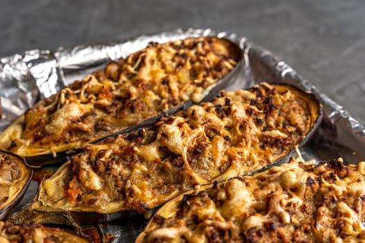 eggplant baked with meat on a baking sheet. view from above. close-up. Eggplant halves stuffed with minced meat, spices and cheese, for baking in the oven. Delicious and healthy food.