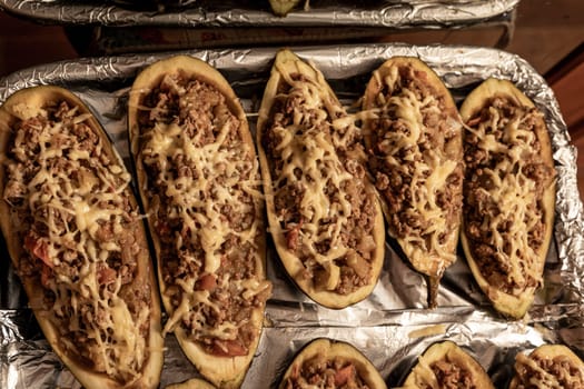 eggplant baked with meat on a baking sheet. view from above. close-up. Eggplant halves stuffed with minced meat, spices and cheese, for baking in the oven. Delicious and healthy food.