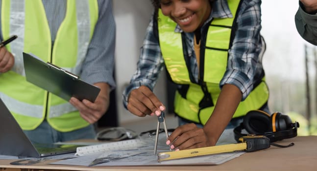 Architect team working with blueprints for architectural plan, engineer sketching a construction project on table in working site.