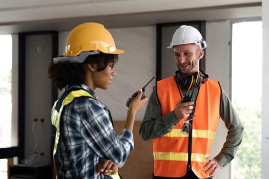 Female male engineers holding walkie talkie radios and inspecting construction site.