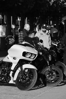 Vertical grayscale of three male standing by a white chopper motorcycle. Harley Davidon in Duesseldorf, Germany.