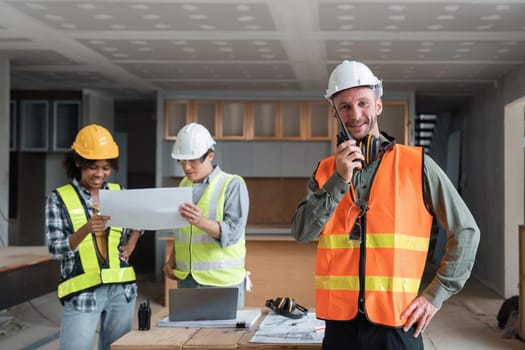 Portrait of male engineer holding walkie talkie and male engineer female with working together inspection housing estate project at the construction site.