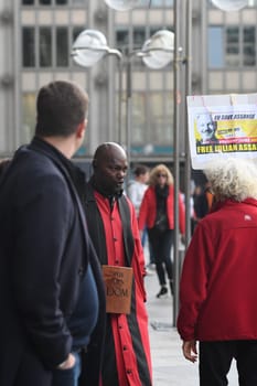 Vertical shot of the Cathedral servant in front of Cologne Cathedral in a red robe arguing with a Free Assange demonstrant, Cologne, Germany