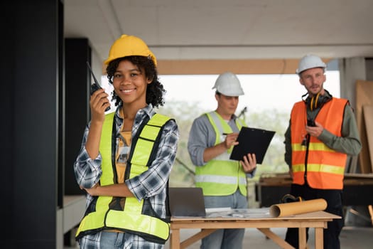 Portrait of female engineer holding walkie talkie and male engineer with working together inspection housing estate project at the construction site.