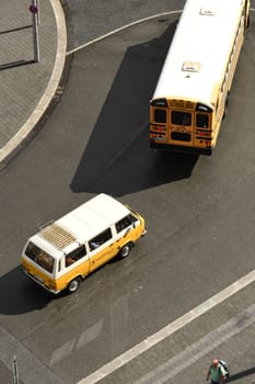 Aerial view of an American school bus with a white and yellow small bus coming from behind