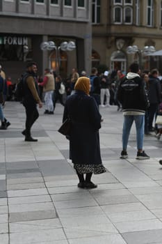 Vertical shot of a woman wearing a hijab standing in front of Cologne Cathedral, Cologne, Germany