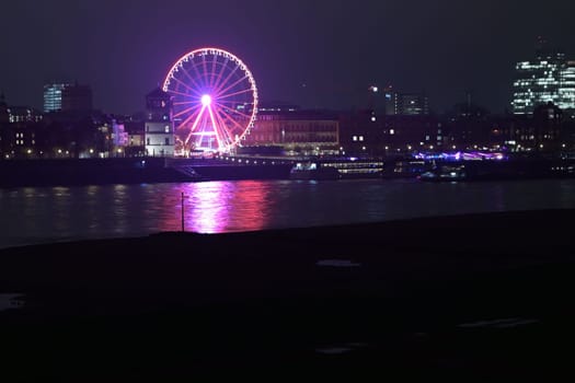 Rhine riverbank by night with castle tower and Ferris pink wheel in Duesseldorf, Germany