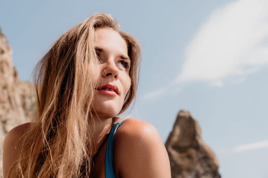 Woman travel sea. Young Happy woman in a long red dress posing on a beach near the sea on background of volcanic rocks, like in Iceland, sharing travel adventure journey