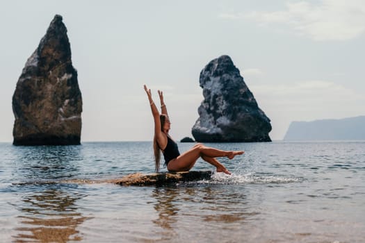 Woman travel sea. Young Happy woman in a long red dress posing on a beach near the sea on background of volcanic rocks, like in Iceland, sharing travel adventure journey