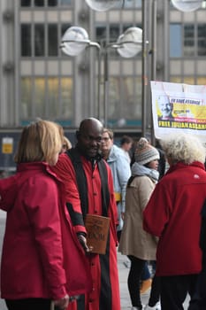 Vertical shot of the Cathedral servant in front of Cologne Cathedral in a red robe arguing with a Free Assange demonstrant, Cologne, Germany