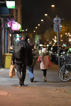 Rear of a father with two children walking along the row of stores in Oberkassel, Duesseldorf, Germany