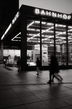 Vertical shot of the entrance to Potsdamer Platz train station with people walking by at night