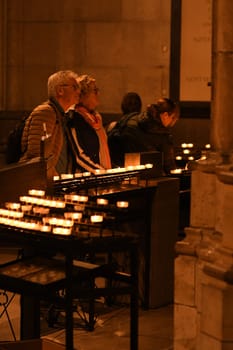 People hold devotions in front of a sea of candles at Cologne Cathedral in Cologne, Germany