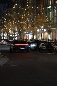 A black Porsche Cayenne drives at night along the Christmas illuminated Koenigsallee in Duesseldorf, Germany