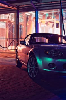 Silver JDM convertible at night in front of a car wash and neon lights