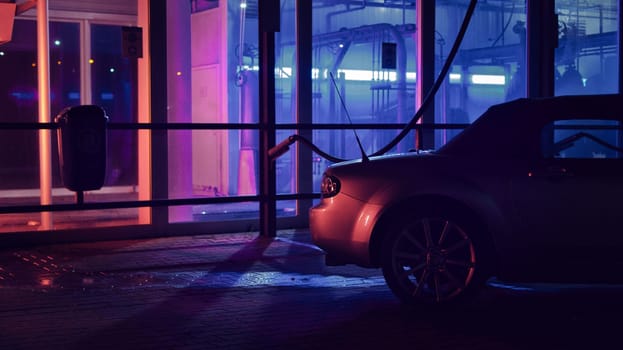 Silver JDM convertible at night in front of a car wash and neon lights