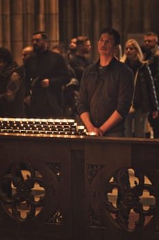 Vertical shot of people holding devotions in front of a sea of candles at Cologne Cathedral, Germany